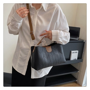Detail of black tote bag featuring V-shaped stitching with contrast brown shoulder strap