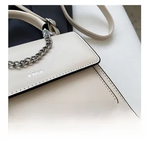 Dettaglio delle cuciture precise e della catena d'argento sulla borsa beige