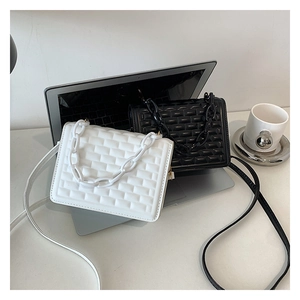 Detail of square embossed crossbody bags in black and white with matte chain straps