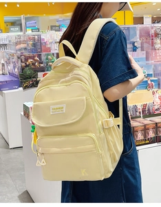 Detail of light yellow backpack with side compression straps and water bottle pocket