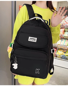 Detail of black waterproof nylon backpack with white K embroidery and cute plush bunny charm