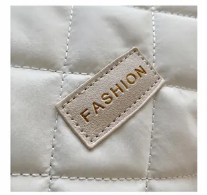 Detailed macro shot of white quilted fabric and embossed leather 'FASHION' emblem on bag