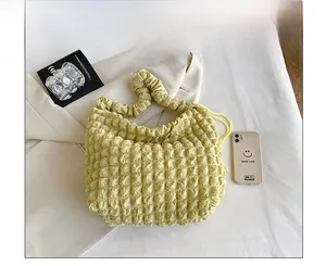 Detail of yellow popcorn textured shoulder bag with scrunchie handle and drawstring design
