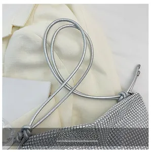 Close-up of sparkling silver rhinestone handbag featuring a knotted metallic shoulder strap