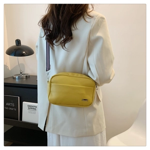 Detail of yellow lychee texture leather crossbody bag with wide purple striped strap
