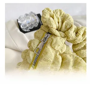 Detail view of the silver metal zipper and soft pleated texture on the yellow cloud bag