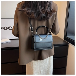 Vista posteriore di una modella con borsa in pelle nera, catena e logo inciso
