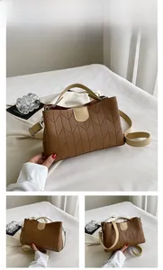 Detail view of brown quilted handbag with V-stitch texture and beige top handle design