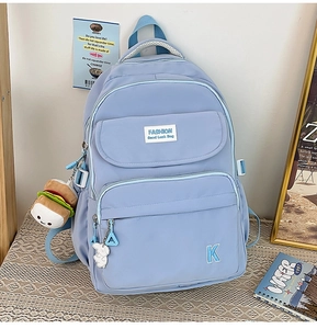 Detail showing light blue waterproof nylon backpack with plush burger and letter pendants