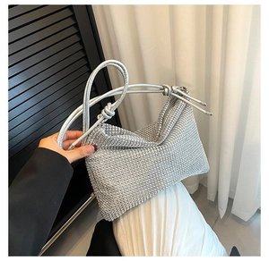 Detailed view of silver rhinestone handbag with knotted strap held by model