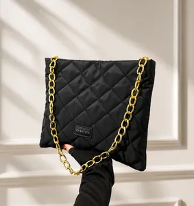 Detail of black quilted bucket bag featuring fashion label and gold chain strap