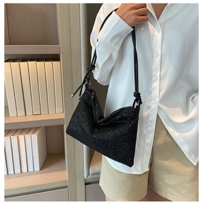 Detail of elegant black rhinestone shoulder bag with stylish knotted strap and zipper