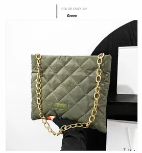 Detail of green quilted puffer bag with gold chain and fashion logo rubber tag