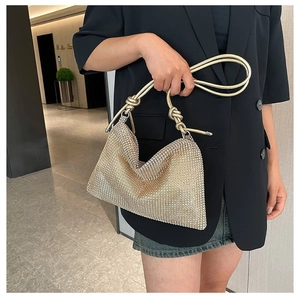 Close-up of golden rhinestone shoulder bag with twisted handle on a black blazer