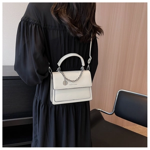 Dettaglio borsa a tracolla bianca in pelle PU con catena d'argento e ciondolo logo