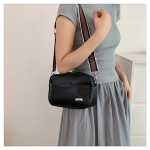 Litchi pattern black camera bag with adjustable striped wide shoulder strap on model