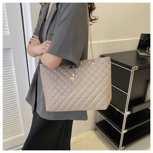 Beigefarbene Stepptasche mit goldener Kette und Reh-Anhänger am weiblichen Model