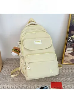 Detail of a creamy yellow water-resistant nylon backpack with a plush burger charm