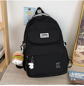 Close-up of black nylon backpack with burger plush keychain and breathable straps