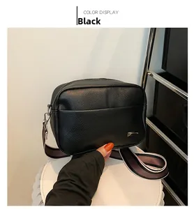 Detail of black lychee grain camera bag featuring a stylish wide striped fabric strap