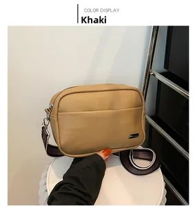 Close-up of khaki litchi grain leather camera bag with striped wide shoulder strap