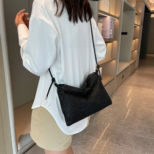 Detail of black rhinestone crossbody bag showing shimmering texture and long shoulder strap