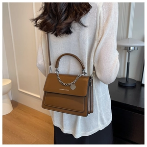 Borsa a tracolla in pelle marrone con catena d'argento indossata da modella in interni