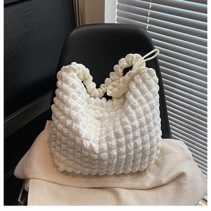 Detail of white popcorn textured hobo bag with soft fabric and pleated design on chair