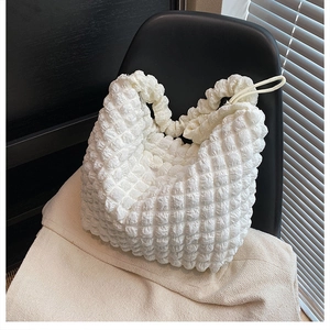 Detailed view of white popcorn texture fabric on a minimalist soft cloud shoulder bag
