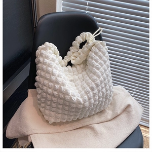 Detailed view of pearl white bubble textured fabric and drawstring closure on the shoulder bag