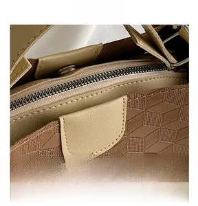 Detailed close-up of smooth metal zipper and 3D geometric texture on the leather handbag