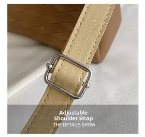 Detail of adjustable beige leather strap with silver metal buckle and brown tote bag