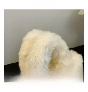 Detailaufnahme des flauschigen Plüschgriffs einer cremefarbenen Kunstfell-Handtasche
