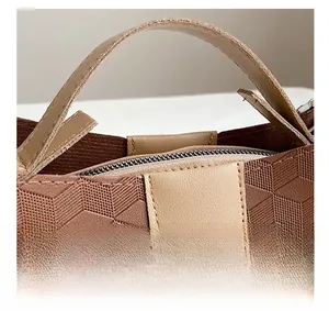 Detail showing geometric 3D embossed texture and leather handle on coffee brown tote bag