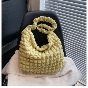 Detail shot of the pale yellow bubble textured fabric and pleated design of the shoulder bag