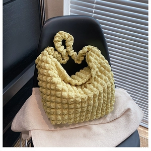Detail showing the textured bubble popcorn fabric and zipper of the yellow shoulder bag
