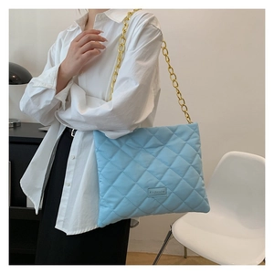 Close-up of light blue quilted crossbody bag with chunky gold chain strap and fashion label