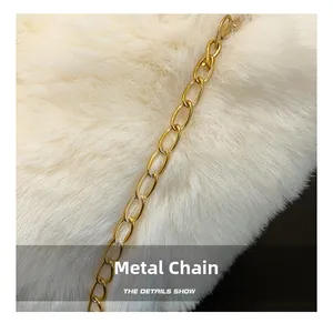 Detailaufnahme der flauschigen weißen Webpelz-Textur und der glänzenden goldenen Kette