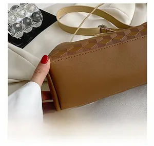 Close-up of brown geometric embossed leather handbag with handmade stitching details