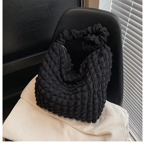 Detail of black cloud bag featuring pleated bubble texture and metal zipper closure