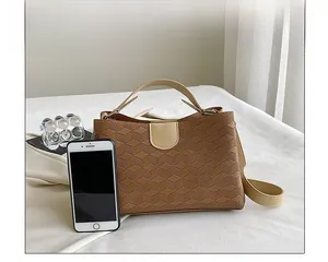 Detailed view of brown tote bag with geometric embossing and beige leather flap