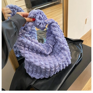 Detail showing the textured bubble cloud fabric and zipper closure of this purple handbag