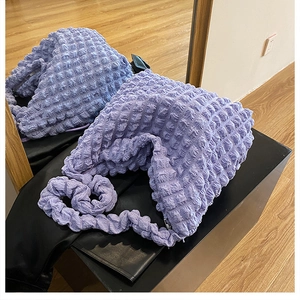 Detail of lavender puffer hobo bag with quilted popcorn texture on a display stand