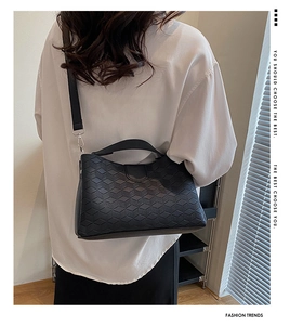 Detail of black geometric embossed tote bag with adjustable strap on female model