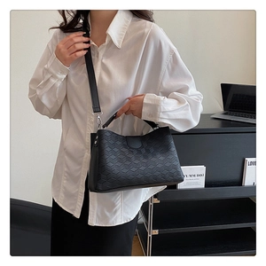Detail of black tote bag with quilted diamond pattern and detachable shoulder strap