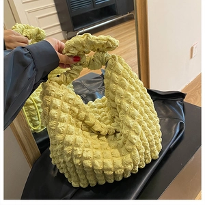 Detail of light yellow popcorn texture shoulder bag showing elastic bubble fabric pleats