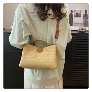 Detail of minimalist beige handbag showing 3D geometric texture and brown leather strap
