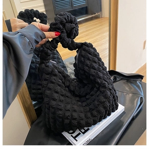 Detail view of the black textured bubble fabric and unique knotted handle on the bag