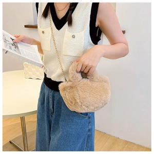 Detail der weichen khakifarbenen Plüschhandtasche mit goldener Kette am Modell zu Hause