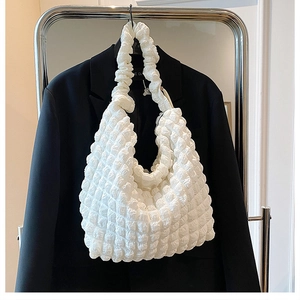 Detailed close-up of the textured popcorn fabric and pleated strap on white cloud bag